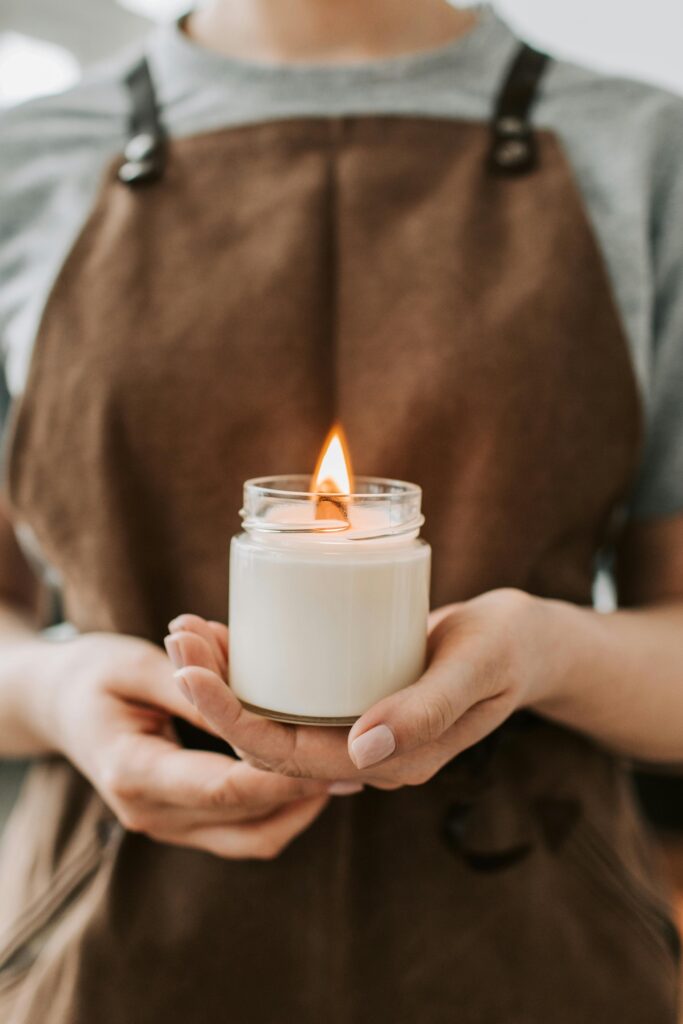 pexels photo 6755859 6755859 Warm ambient lighting with a focus on handmade candle in a jar held by a craftsman wearing an apron.